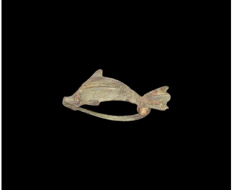 2nd century AD. A bronze plate brooch formed as a dolphin with media rib, scooped tail with enamelled cells, deeply curved bo