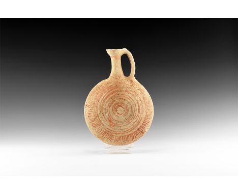 11th-6th century BC. A terracotta flask with biconvex body, trumpet -shaped neck with loop handle, concentric rings and radia