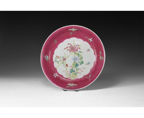 19th century AD. A white ceramic glazed dish with textured border, reserved flowers on a pink field, central spray of flowers