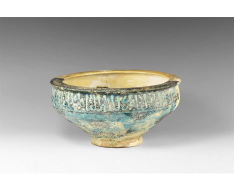 11th century AD. A ceramic blue glazed bowl with wide rim, flat shoulder with Arabic inscription; sloping body with geometric