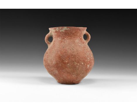 3rd millennium BC. An early Bronze Age terracotta jug with narrow foot, bulbous body, flared rim, two loop handles to the sho