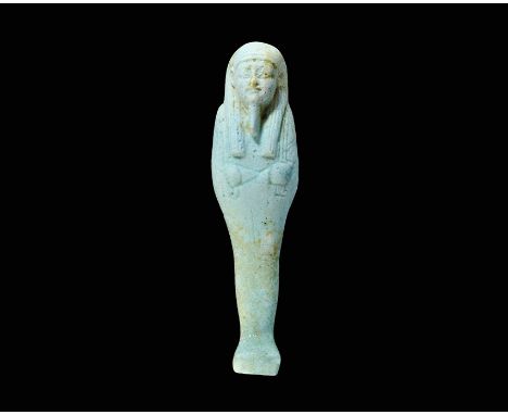 Late Period, 664-332 BC. A finely-modelled light pale blue-green glazed composition shabti with tripartite wig and plaited be