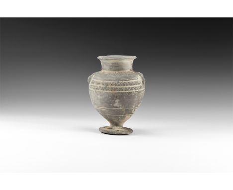 1st millennium BC. A greyware ceramic jar with broad discoid foot, bulbous body, deep shoulder, short neck with everted rim; 