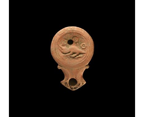 1st century AD. A ceramic oil lamp with round discus, volute-scrolls to the nozzle with crescentic outer edge; low-relief ima