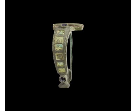 2nd century AD. A bronze brooch with barrel-shaped head, curved flat-section bow with enamelled roundels and rectangular rece