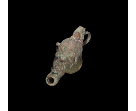 2nd-3rd century AD. A bronze oil lamp with body formed as a grotesque satyr face, circular base and loop to the back; hole to