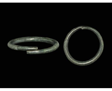 800-500 BC. A round-section penannular bronze bracelet with butted ends, bands of vertical and diagonal hatching to the outer