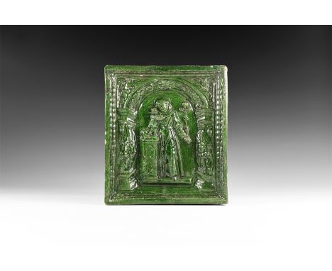 16th-17th century AD. A ceramic stove tile with green glaze to one face with image of a nimbate monk holding a cross and supp