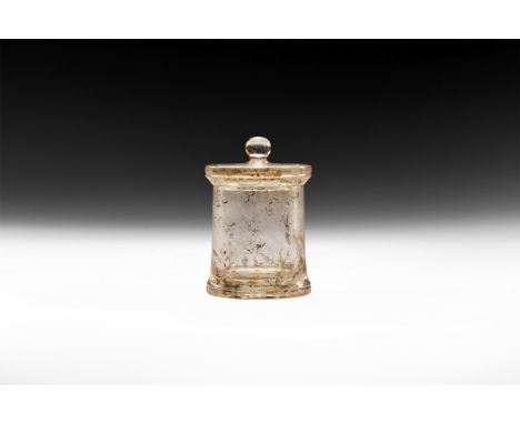 7th-8th century AD. A rock crystal cylindrical container with flared base and concentric circles to the underside, discoid li