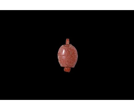 Amarna Period, 1353-1336 BC. A red glazed composition amuletic pendant of a date with attachment loop at each end. Cf. Andrew