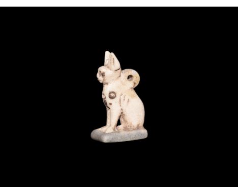 Third Intermediate Period, 1069-702 BC. A white glazed composition amulet of Bastet in cat form sitting on a rectangular base