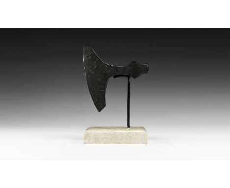 9th-11th century AD. An iron axehead with curved edge, T-shaped blade, broad socket with lateral flanges, hammer-face to the 