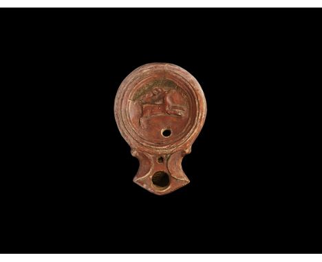 2nd century AD. A ceramic oil lamp with round discus, low-relief image of a running deer; volute-scrolls to the nozzle.  36 g