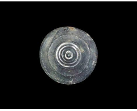 2nd millennium BC. A large bronze discoid plaque with central stud, concentric repoussé bands and raised ribs, loop to the re