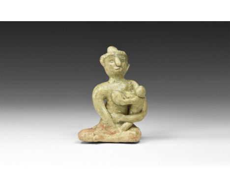 12th-16th century AD. A green-glazed ceramic figurine of a nude seated female suckling a baby in her arms; hollow to the unde