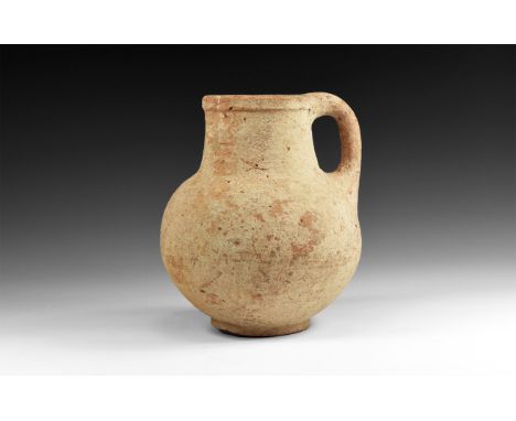 1st-2nd century AD. A ceramic buff coloured flagon with rolled rim and pinched end for lip; tapering neck with sloping should
