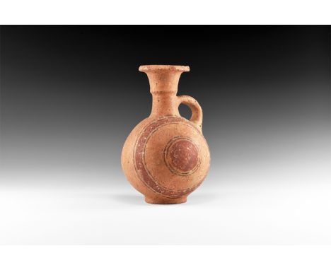 12th-10th century BC. A terracotta globular flask with trumpet-shaped neck with median carination, everted rim, strap handle 