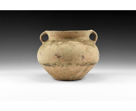 1st-3rd century AD. A creamware ceramic jar with convex lower body, rounded shoulder, flared mouth with two strap handles; pa