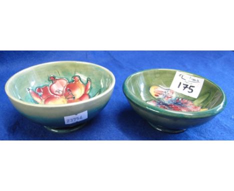 Two similar Moorcroft pottery tube lined, florally decorated, pedestal pin dishes on a green ground, marked to base. (2)(B.P.