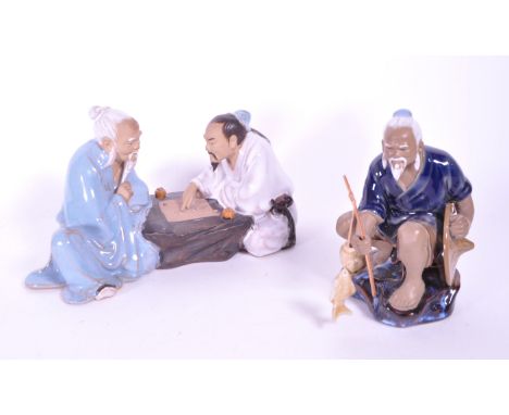 Two vintage 20th century Chinese pottery ceramic mud men figures, comprising of a fisherman on a rock and two men playing a b