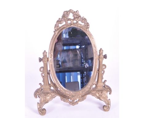A vintage 20th century gilt tabletop swing mirror. Neoclassical French style on scrolled foliate trestle legs. Oval glass mir