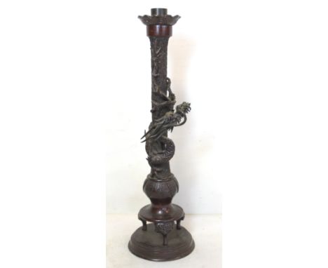 Late 19th/early 20th century Oriental lacquered bronze candlestick with lobed drip tray, the cylindrical column with archaic 