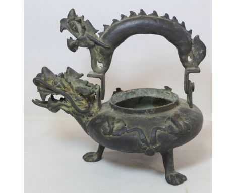 Chinese bronze wine kettle of circular squat form with a dragon spout and handle, three paw feet and lotus decoration, lackin