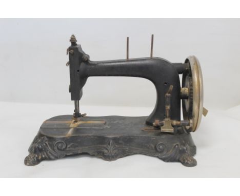 19th century black japanned manual sewing machine, no maker's name, the lobed plinth with four paw feet and scroll moulding, 