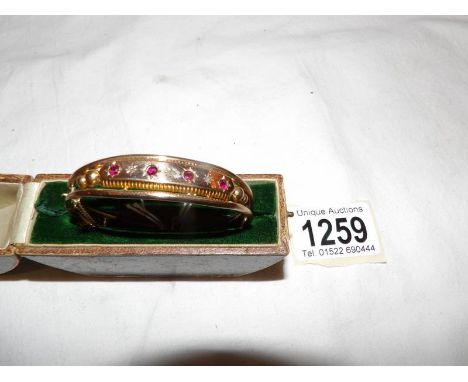 A gold coloured metal bangle (no hm found) set ruby coloured and paste stones, a/f