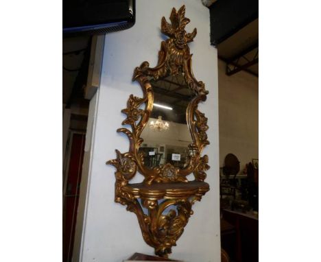 A gilt framed mirror with display shelf