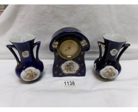 A small 3 piece ceramic clock garniture depicting cherubs