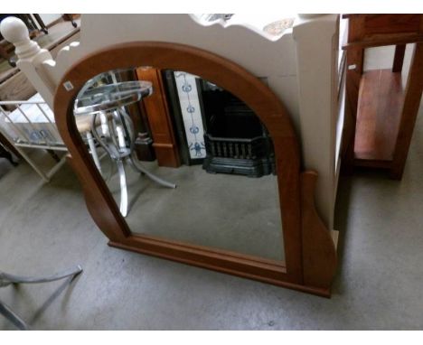 A wood framed arch topped over mantel mirror