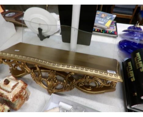 A gilded wall shelf with glass top