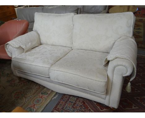 Good quality modern cream ground foliate upholstered two seater sofa with shaped arms standing on brass casters.   (B.P. 21% 