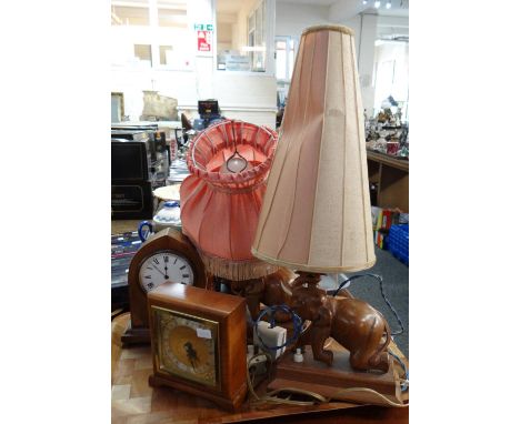 Two carved wooden table lamps in the form of elephants with shades and two small mantel clocks; one an Elliott clock and an a