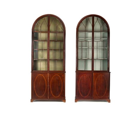 Each reeded arched cabinet with Gothic glazed doors, fitted with four shelves, the lower half with a pair of cupboard doors e