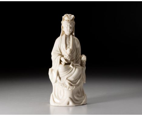 The Goddess of Mercy seated on a high rocky plinth, her contemplative face beneath a high chignon covered by a veil cascading