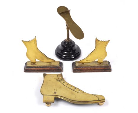 A LATE VICTORIAN BRASS TRIVET IN THE FORM OF A BOOT, 21cms, a pair of brass flat boots, on oak plinth bases, and a late Victo