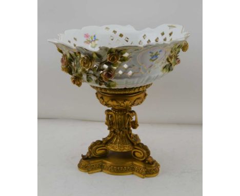 A CONTINENTAL CERAMIC BOWL upon a gilt brass base, the bowl with applied flowers, hand painted and reticulated, 28cm diameter