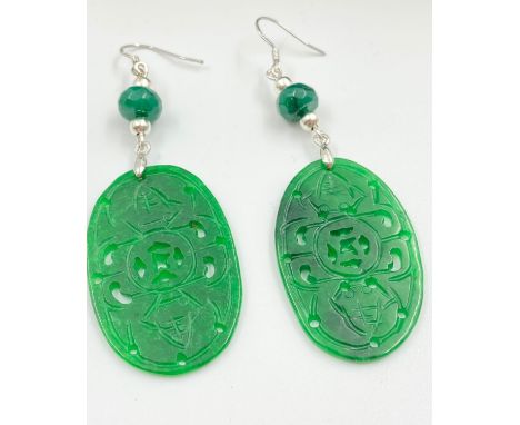 A pair of Chinese, intricately carved green jade earrings, presented in a green marble box. Earrings length: 7 cm. 