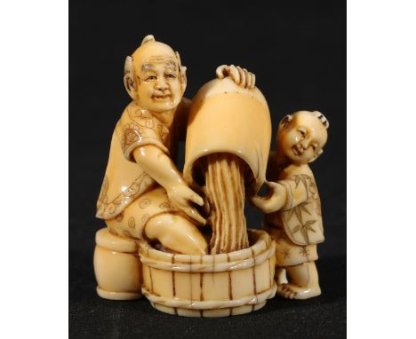 Japanese carved ivory okimono with netsuke himatoshi depicting a man and a boy pouring water into a wooden basin, signed to b