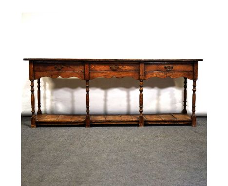 Elm and pine dresser base, rectangular boarded top with cleated ends, three drawers, shaped apron, turned legs, pot boards ba