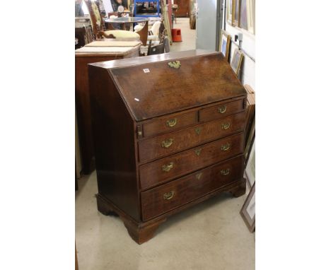 George III Oak Bureau, the sloping front opening to a fitted interior, over two short and three long drawers, raised on brack