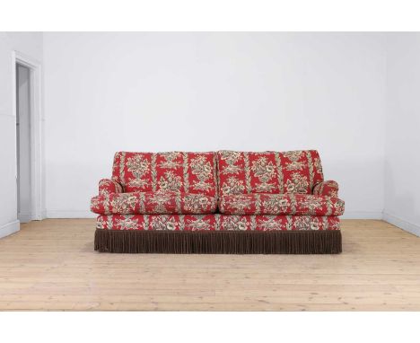 A three-seater sofa in the Howard & Sons style, of recent manufacture, upholstered in red printed floral fabric with tasselle