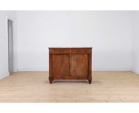 A Biedermeier mahogany cabinet, early 19th century, German, with a grey marble top, above a frieze drawer and a pair of cupbo