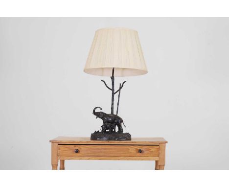 A bronze table lamp, 20th century, modelled as two elephants on a naturalistic base and column, with pleated shade, 30cm wide
