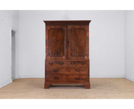 A George III mahogany linen press, c.1760, the dentil-moulded cornice with blind-fret banding, above two panelled doors, over