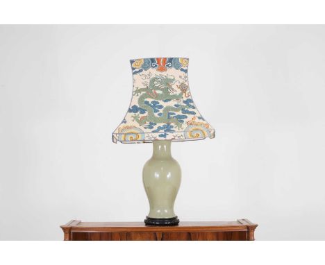 A celadon-glazed pottery lamp, of recent manufacture, Chinese, of baluster form on a hardwood base, with a 23-inch linen-cove