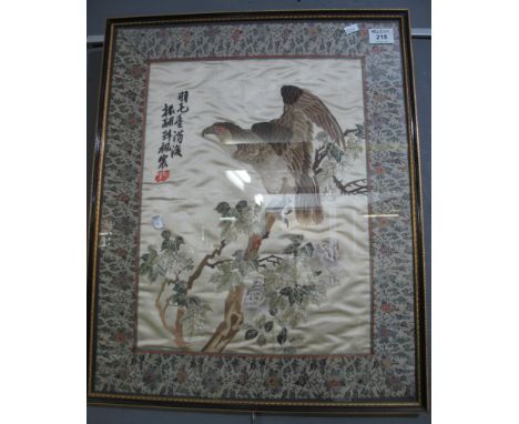 A probably Chinese oriental silk embroidered panel depicting a bird of prey on branch with leaves and flowers within a damask