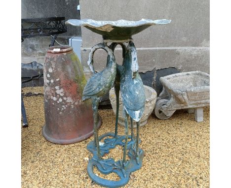 A painted metal birdbath, the base in the form of three storks, 44 cm wide, a composite stone plinth, 30 cm wide